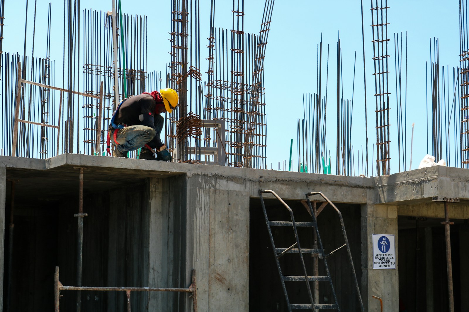 Photo by Ivan Henao man kneeling on unfinished building during daytime